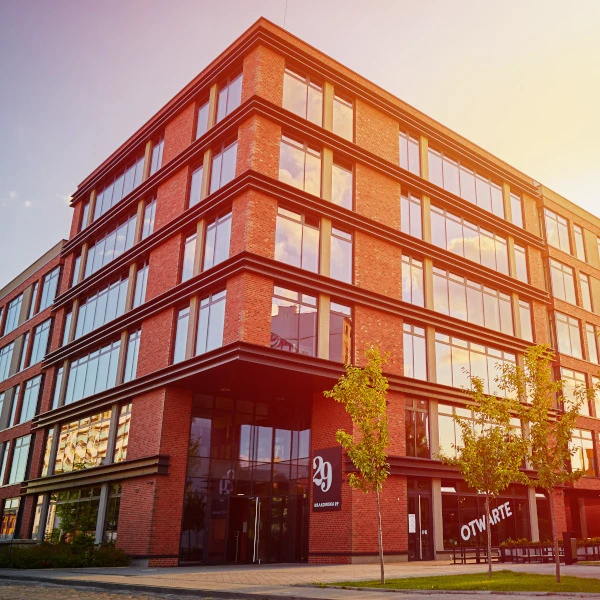 Modernes Bürogebäude aus rotem Ziegelstein charakterisiert durch große Fensterflächen und warmes Sonnenlicht